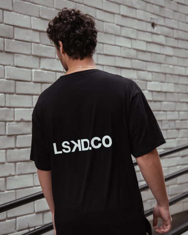 man in black crew neck t-shirt standing near brick wall